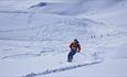 Person on the way down a mountain on randonee skis.