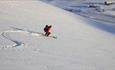 Person on the way down a mountain side on randonee skis.