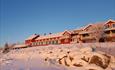 Ein rotes Holzhotell in warmen Winterlicht in schneebedeckter Landschaft