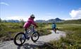 Kinder radeln in der Beitostølen Trail Arena. Naturschöne Umgebung mit dem Bitihorn im Hintergrund.