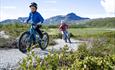 Kinder radeln in der Beitostølen Trail Arena. Naturschöne Umgebung mit dem Bitihorn im Hintergrund.