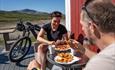 Syklister tar en pust i bakken og koser seg i solterrassen med vaffel og kaffe