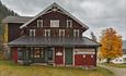 An old farm building with a farm store, a lawn, driveway and a yellow, autumn-coloured maple tree