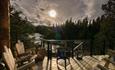 Wooden deck with solid wooden chairs with view to a waterfall against the sun