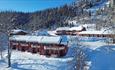 Red semi-attached wood buildings in a snow-covered hillside surrounded by forest