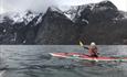 kajakk på en fjord med snødekte fjell bakenfor