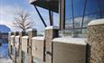 Modern two-story building of glass, stone and wood with roof top terrace.