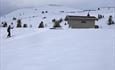 Skibua ligger ca 3 km fra Gamlestølen, en kort avstikker fra løypa opp mot Jomfruslettfjellet.