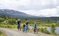 A family cycles on a gravel road along Lake Vasetvatnet.