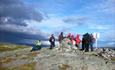 A group of hikers at the cairn on top of a mountain.