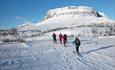 Cross-country skiers in front of a mountain a sunny winter's day.