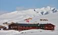 En fjellstue og et knippe hytter i et nedsnødd høyfjellslandskap