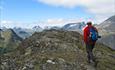 Hiker on a ridge with a view to high mountain peaks