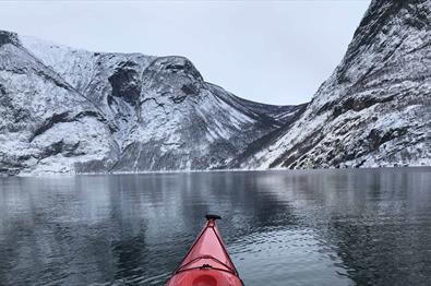 Kajakk med høye snødekte fjell foran