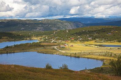 Idyllic surroundings with farm roads, cabins and lakes at Nordre Fjellstølen. In the background the Makalaus mountain massif with its steep hillsides
