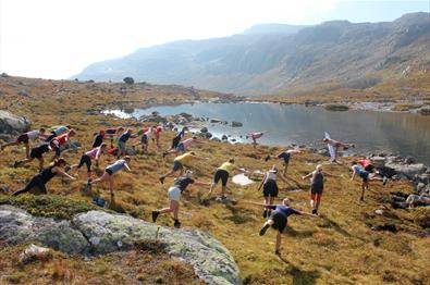 Yoga på fjellet med over 30 deltakere. Fjellvann i bakgrunn.