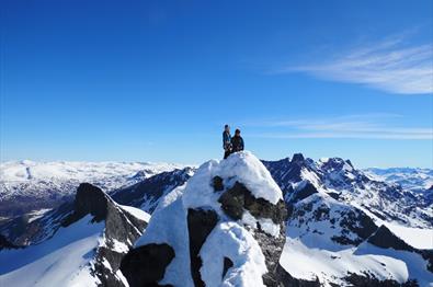 To personer på fjelltopp blant ville fjell i Jotunheimen