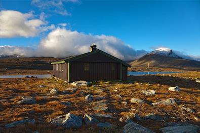 Sulebu en fin høstdag. Hytta ligger rett ved et lite vann, og fjelltoppene troner i bakgrunnen