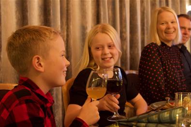 Barn og voksne som koser seg rundt middagsbordet