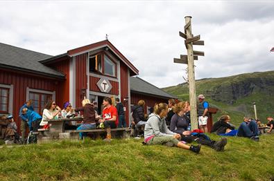 DNT hytte med folk som sitter ute