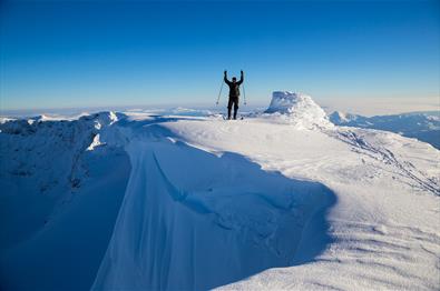 Bergskiläufer auf einem Gipfel mit Schneeüberhang und Abgrund