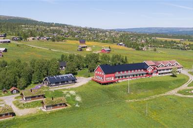 Done footage of a red wooden hotel in a green summer meadow landscape