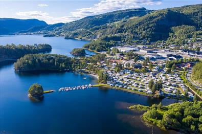 Luftfoto over en stor campingplass ved et vann med strandkant og små øyer.