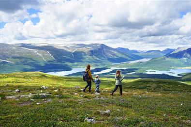 Family hiking in open mountain landscape with lakes and peaks