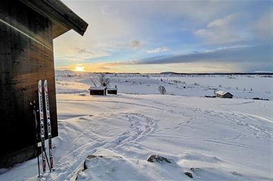Snødekt stølslandskap på fjellet med et par små hytter