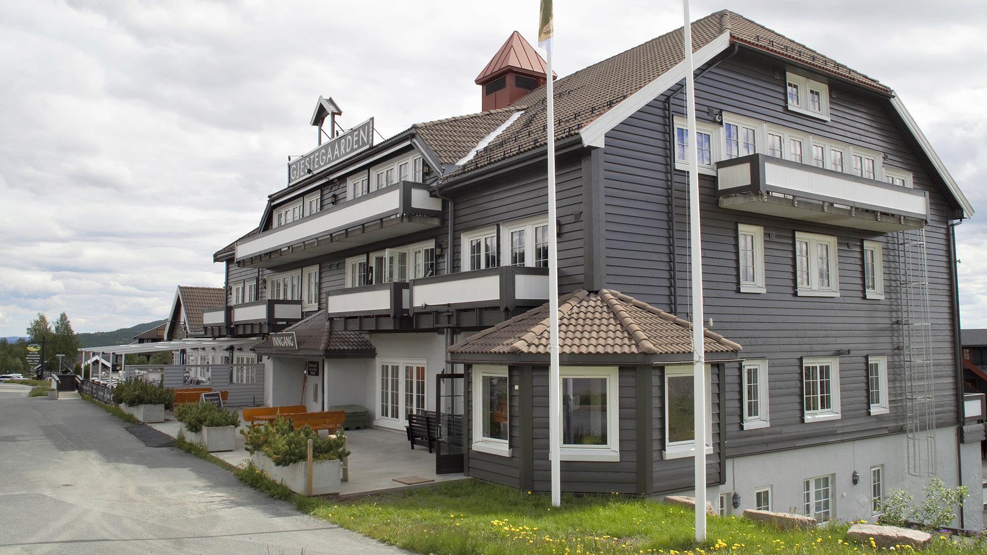 Gray wooden building with white window frames. A lawn and flower pots.