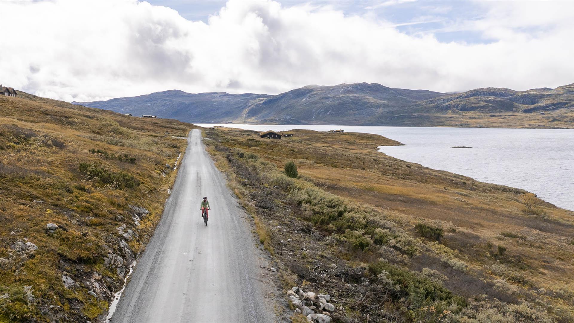 Cyclist on a gravel road in open mountain landscape with large lake