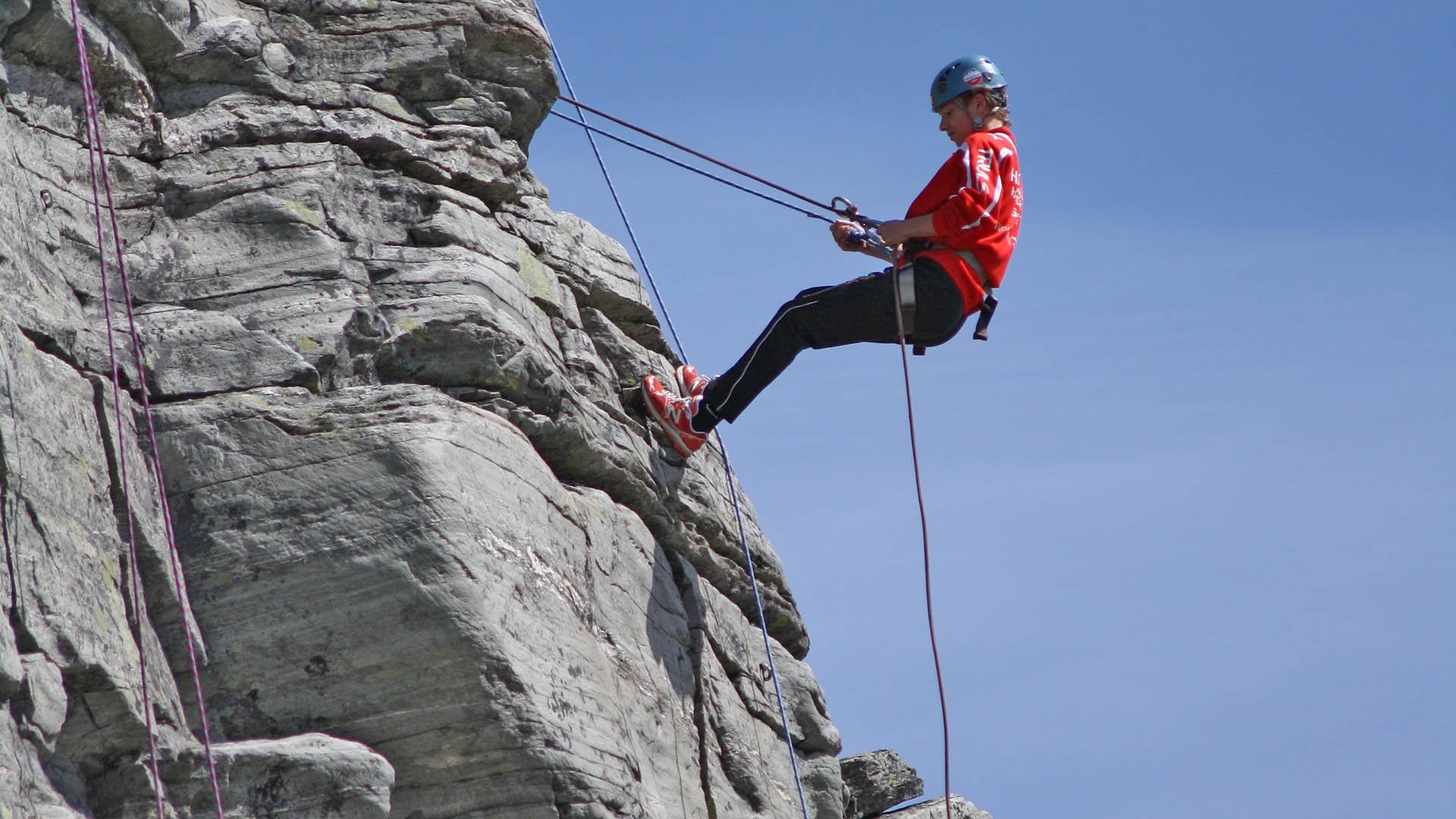 A climber is abseiling on a rock face.
