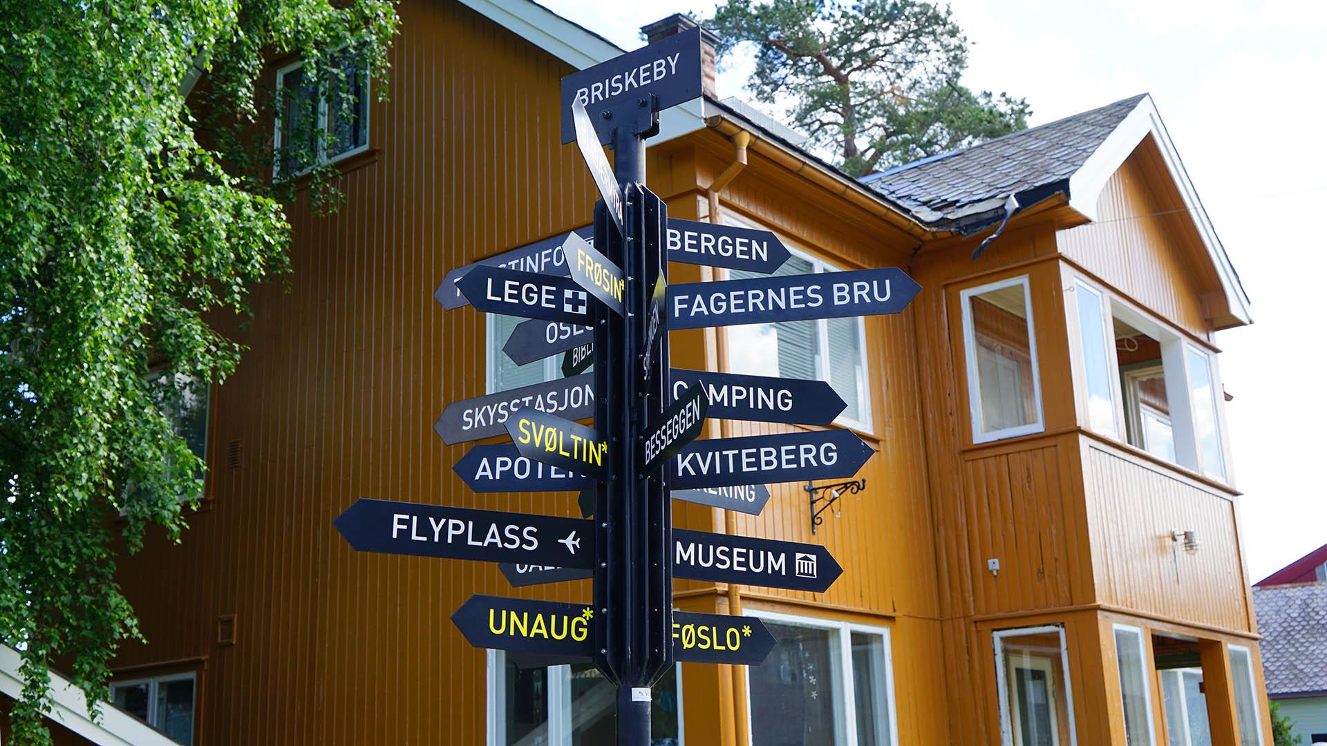 A signpost in front of a yellow-orange wooden building in the old part of the small town Fagernes