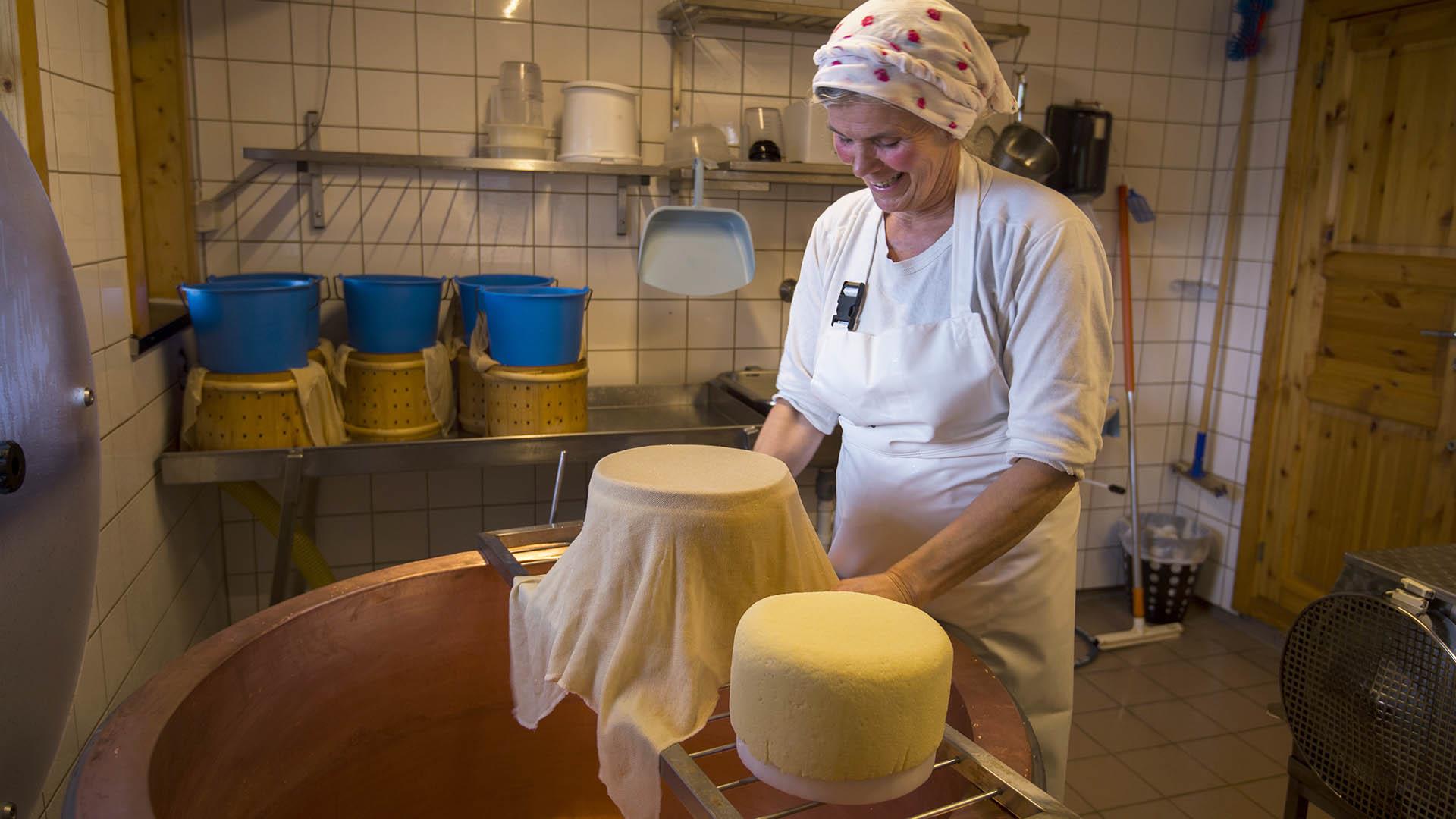 Woman standing in a room making cheese.