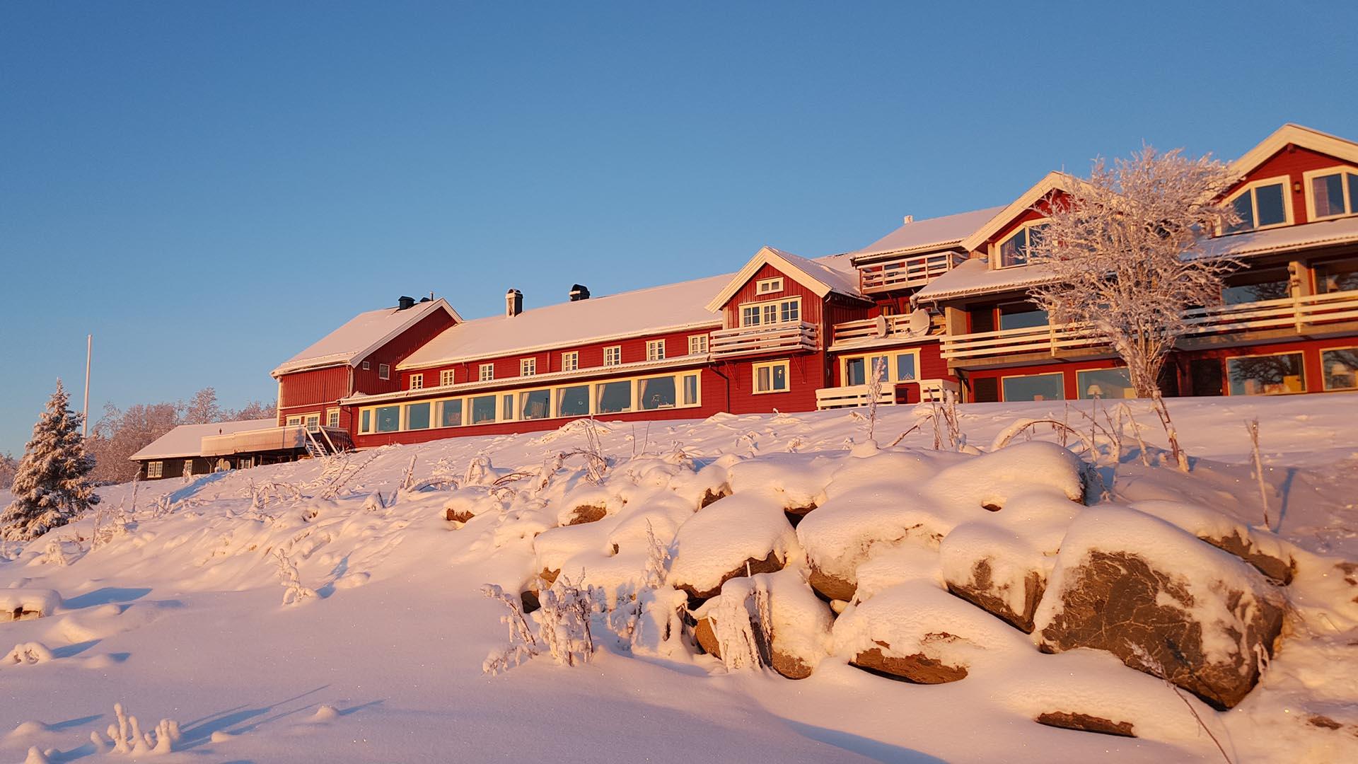 Rødt hotellbygg i varm vintersol med masse snø