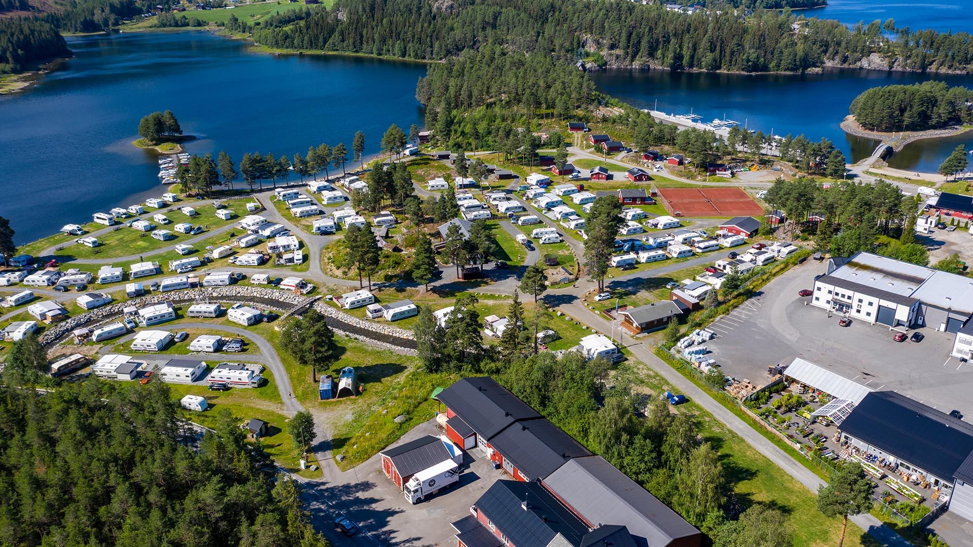 Dronebilde av campingplass ved innsjø med øy og grøntareal