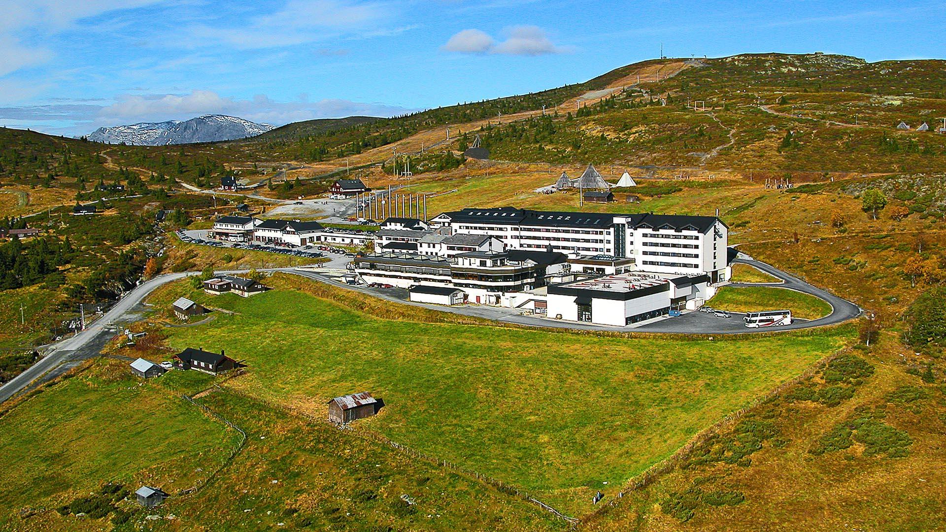 A green mountain hillside with al large white hotel complex