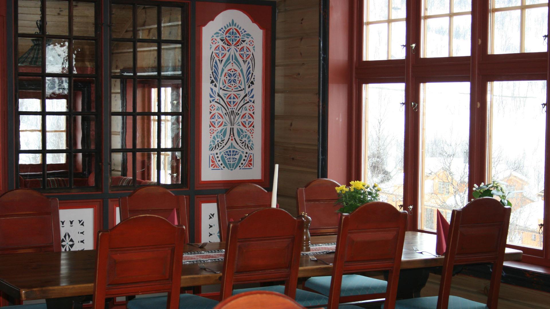 Spisebord i gammelromantisk stil med rosemalt veggpynt på Filefjellstuene.