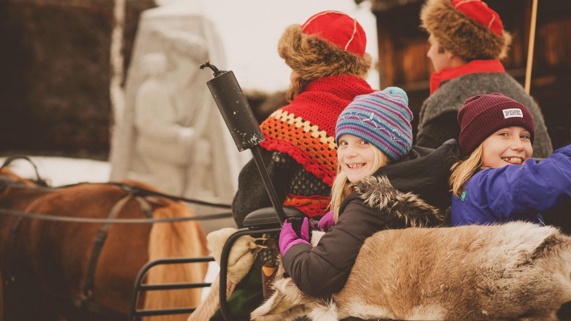 Kinder in einem Pferdeschlitten, der mit Rentierfellen ausgelegt ist, im Valdres Volksmuseum