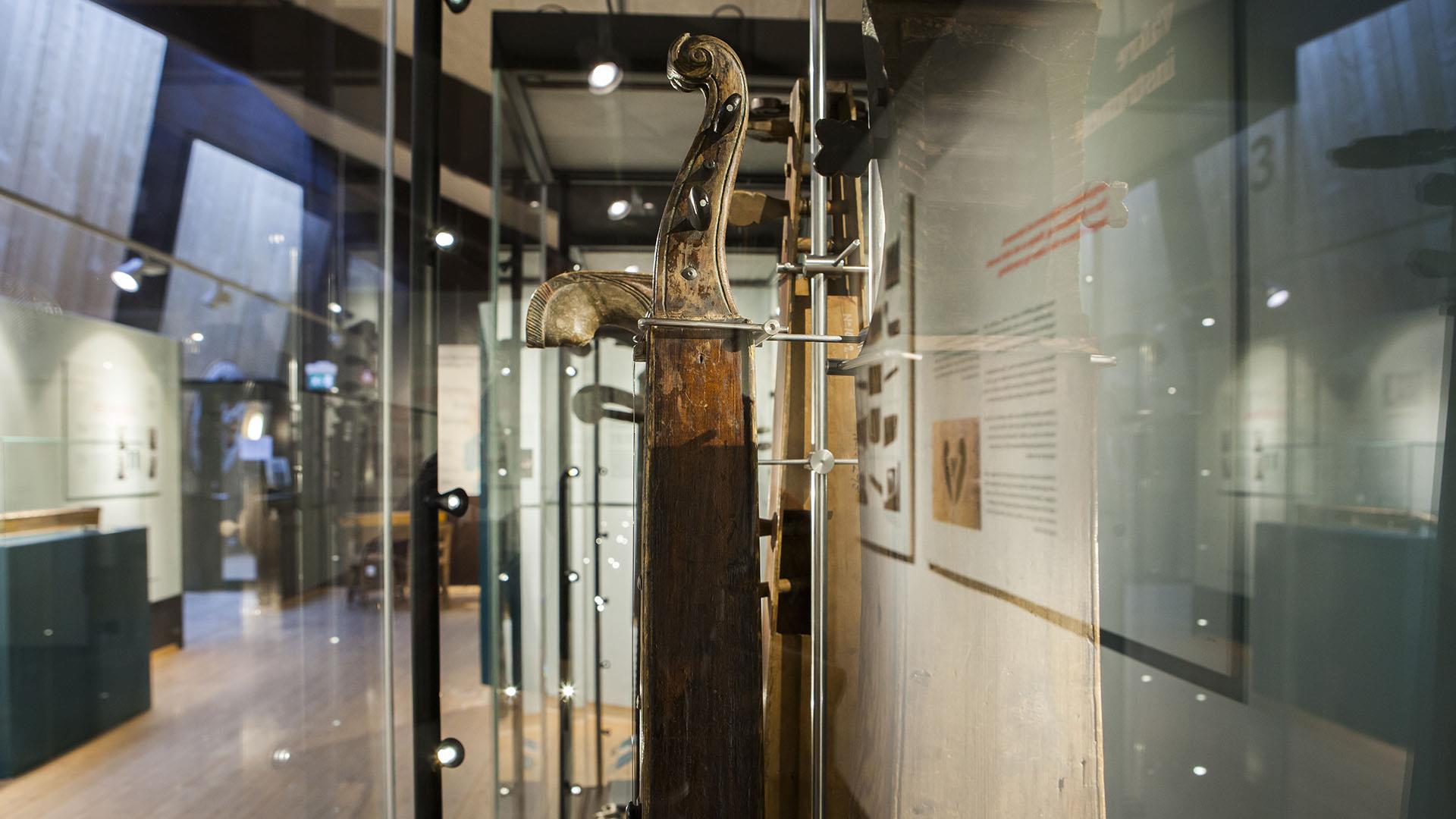 Eine alte Langeleik (zither-ähnliches Musikinstrument) in einem gläsernen Schaukasten in einem Museum.