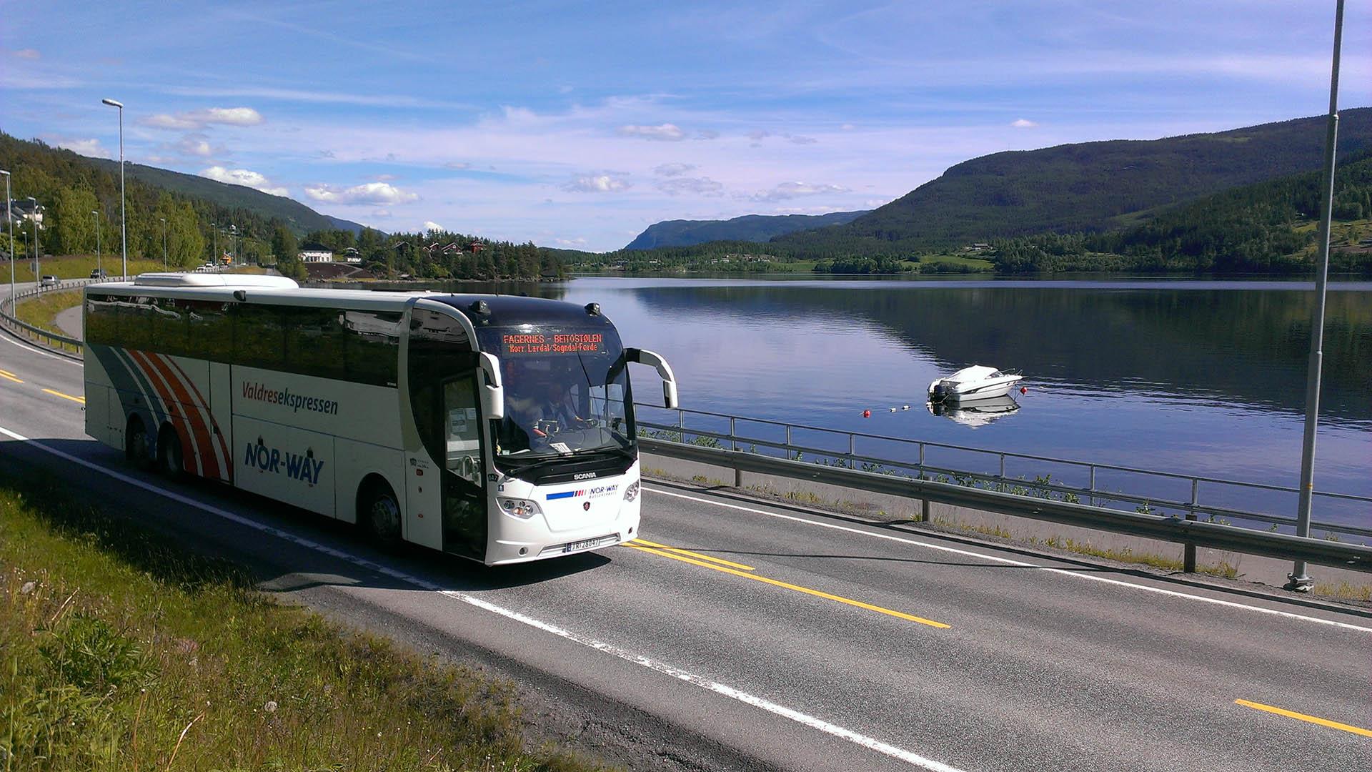 A tour coach on a good road along a lake a sunny summer's day