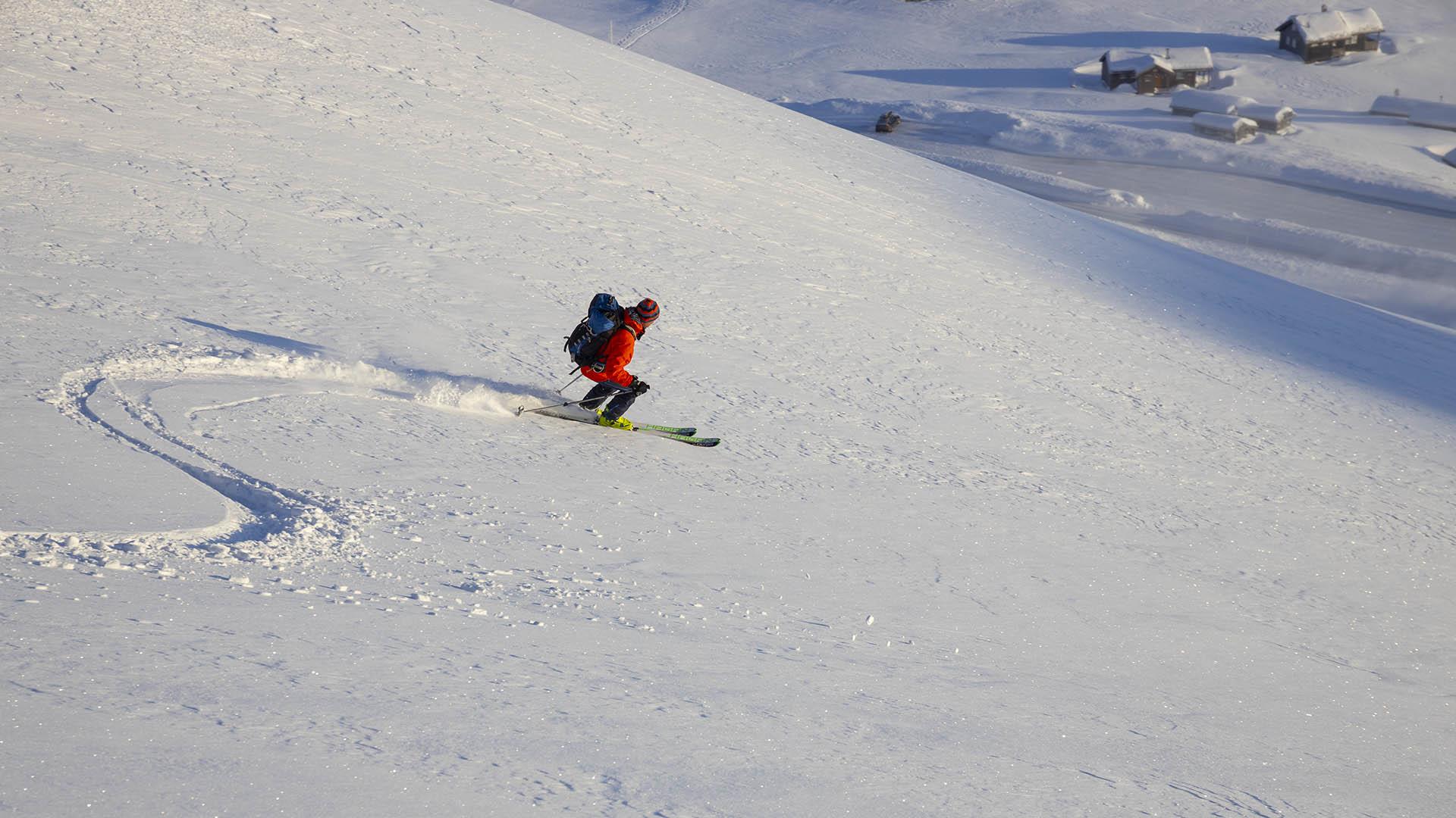 Person on the way down a mountain side on randonee skis.
