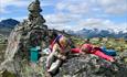 Children take a rest at the summit cairn on Gravolskampen. Some 2k-summits can be seen in the background.