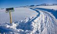 Signage in a intersection of cross-country skiing tracks on a mountain plateau on a steel-blue winter day.