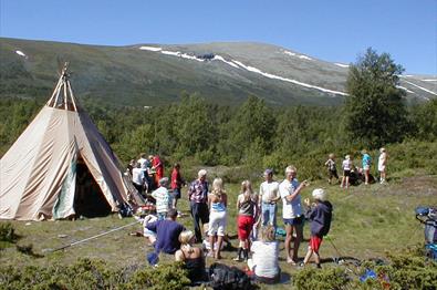 Eine Gruppe Menschen vor einem Samenzelt in den Bergen an einem schönen Sommertag