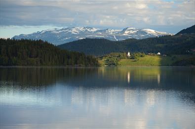 Lake Slidrefjorden seen from the rest area along road E16 near Lomen with the Lomen church and the mountain massif of Vennisfjellet in the background.