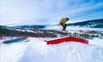 A snowboarder jumps over rails and elements in the ski center at Vaset.