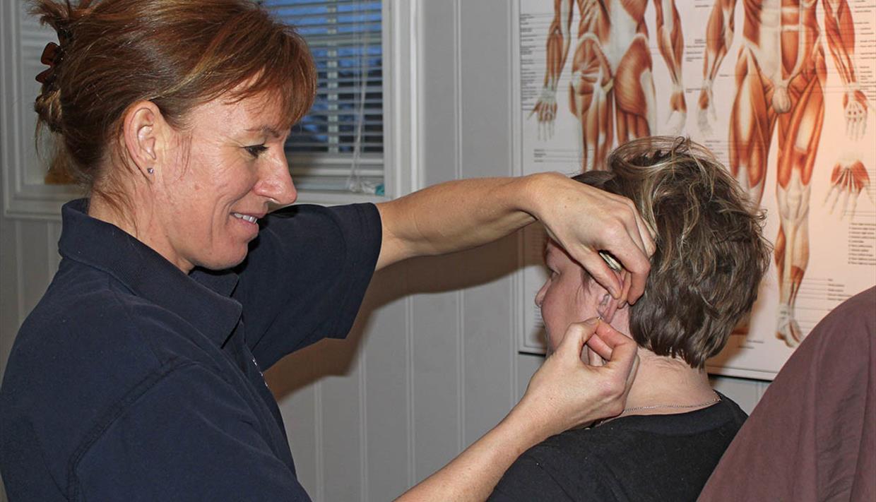 A therapist is giving acupuncture to a patient.