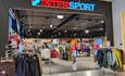 The entrance to Intersport Leira, racks with outdoor jackets and the logo over the entrance.