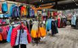 Racks with colourfull outdoor jackets on a grey floor in a sports store